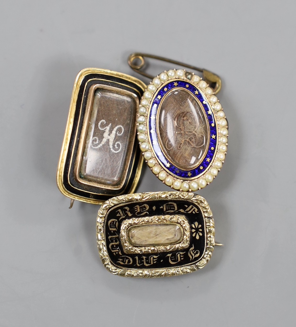 Two George III yellow metal and enamel mourning brooches, with engraved inscriptions, ? Hale, 1795 and Robert Hale, 1812 , both with plaited hair, one mounted with seed pearls(one missing) and a William IV mourning broch
